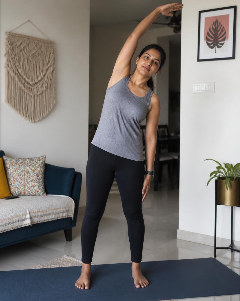 South Asian woman doing a standing side stretch at home